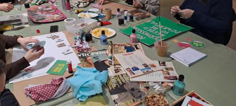 Een tafel ligt bezaaid met knutselmaterialen en kleurrijke panelen, die de workshopdeelnemers pimpen tot protestborden.